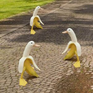 photo of three garden statues of bananas peeled halfway with duck faces and webbed feet